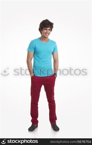 Full length portrait of handsome young man standing with hands in pockets over white background