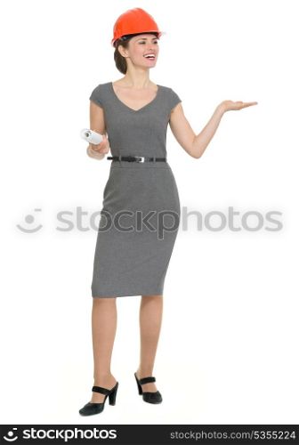 Full length portrait of happy architect woman showing something on empty hand. HQ photo. Not oversharpened. Not oversaturated. Full length portrait of happy architect woman showing something on empty hand isolated