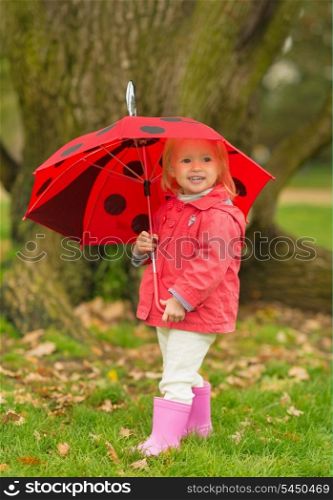 Full length portrait of happy baby with red umbrella outdoors