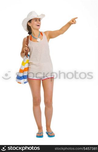 Full length portrait of happy beach young woman pointing on copy space