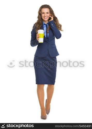 Full length portrait of happy business woman with cup of hot beverage talking cell phone