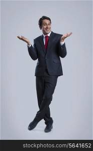 Full length portrait of happy businessman gesturing over gray background