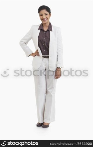 Full length portrait of happy businesswoman with hand on hip against white background