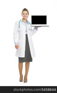 Full length portrait of happy doctor woman showing laptop blank screen