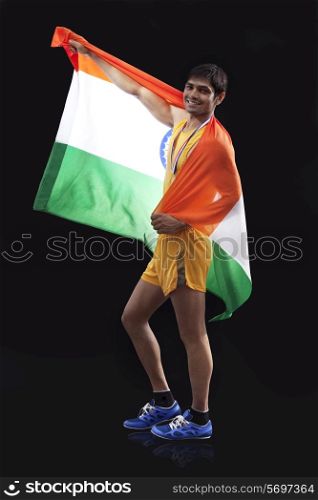 Full length portrait of happy male medalist with Indian flag against black background