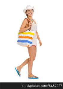 Full length portrait of happy young beach woman in hat going sideways