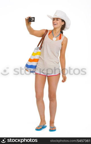 Full length portrait of happy young beach woman in hat taking photo