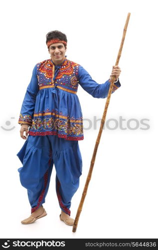 Full length portrait of happy young man in kedia and dhoti holding stick isolated over white background