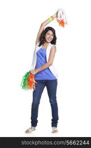 Full length portrait of happy young woman holding Indian tricolor pom poms over white background