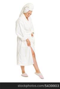 Full length portrait of happy young woman in bathrobe looking on leg