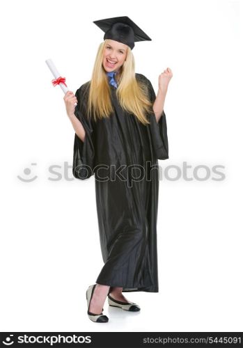 Full length portrait of happy young woman in graduation gown with diploma rejoicing success