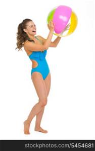Full length portrait of happy young woman in swimsuit playing with beach ball