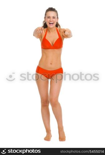 Full length portrait of happy young woman in swimsuit pointing in camera