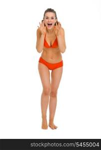 Full length portrait of happy young woman in swimsuit shouting through megaphone shaped hands