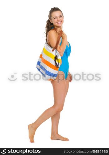 Full length portrait of happy young woman in swimsuit with beach bag