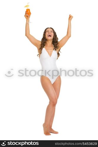 Full length portrait of happy young woman in swimsuit with cocktail rejoicing