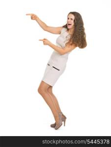 Full length portrait of happy young woman pointing on copy space