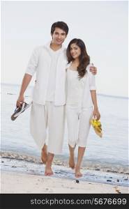 Full length portrait of loving young couple walking together on beach