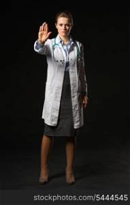 Full length portrait of medical doctor woman showing stop gesture on black background