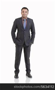 Full length portrait of mid adult businessman with hands in pockets against white background
