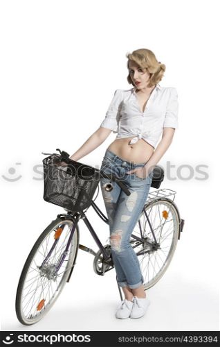 full-length portrait of pretty blonde girl with casual clothes posing near bicycle in summertime