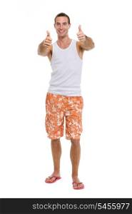 Full length portrait of resting on vacation smiling young guy showing thumbs up