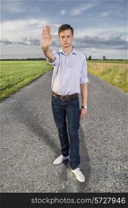 Full length portrait of senior young man showing stop gesture on country road