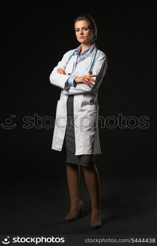 Full length portrait of serious doctor woman on black background