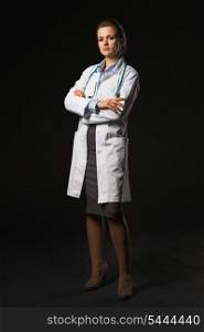 Full length portrait of serious doctor woman on black background