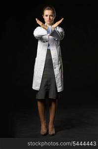 Full length portrait of serious doctor woman showing stop gesture isolated on black