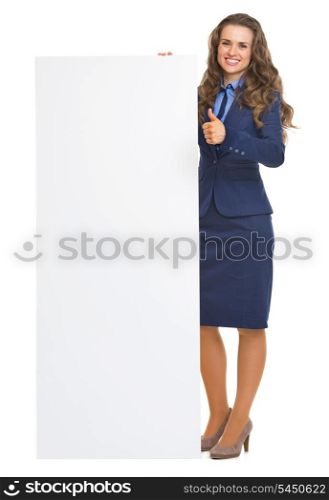 Full length portrait of smiling business woman showing blank billboard and thumbs up