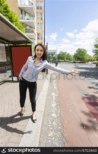 Full length portrait of smiling businesswoman hailing taxi on street