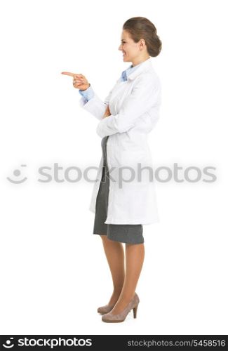Full length portrait of smiling doctor woman pointing on copy space