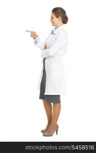 Full length portrait of smiling doctor woman pointing on copy space
