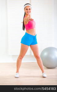 Full length portrait of smiling fitness girl making gymnastics at living room&#xA;