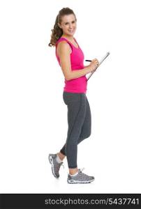 Full length portrait of smiling fitness trainer writing in clipboard