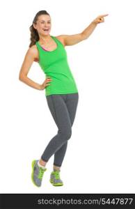 Full length portrait of smiling fitness young woman pointing on copy space