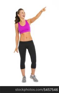 Full length portrait of smiling fitness young woman pointing on copy space