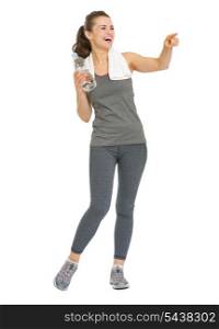 Full length portrait of smiling fitness young woman with bottle of water pointing on copy space