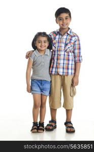 Full length portrait of smiling siblings standing against white background