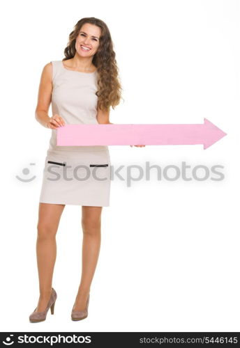 Full length portrait of smiling young woman pointing on copy space with arrow