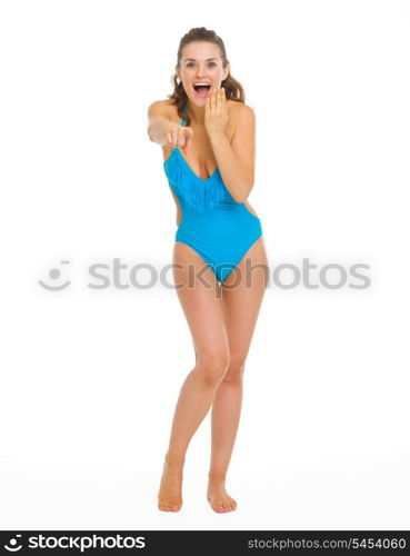 Full length portrait of surprised young woman in swimsuit pointing in camera