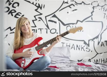Full-length portrait of teenage girl playing guitar in bedroom