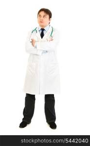 Full length portrait of thoughtful doctor with crossed arms on chest looking up at copy space isolated on white&#xA;