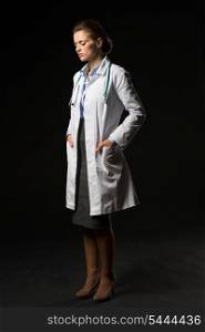 Full length portrait of thoughtful doctor woman isolated on black