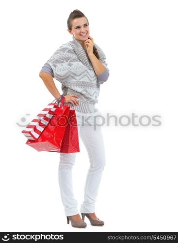 Full length portrait of thoughtful young woman in sweater with shopping bags
