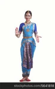 Full length portrait of woman in Bharatanatyam posture over white background