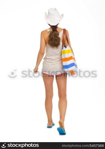 Full length portrait of young beach woman in hat going straight . rear view