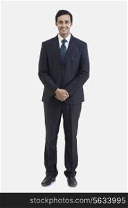 Full length portrait of young businessman in suit isolated over gray background