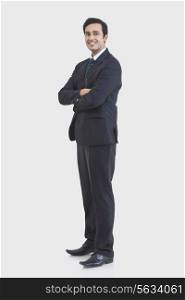 Full length portrait of young businessman in suit isolated over gray background